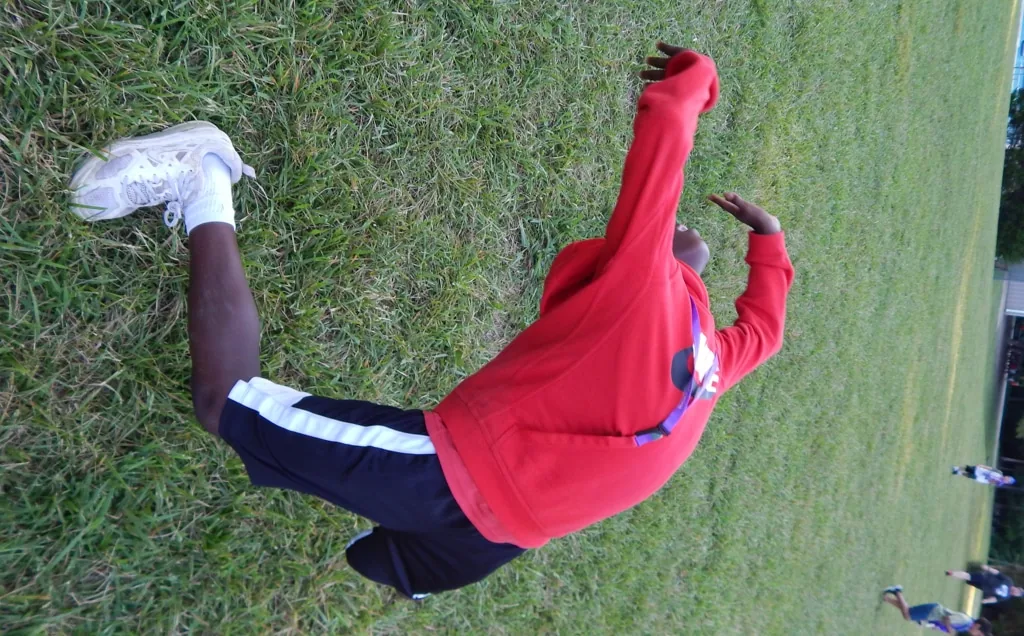 A camper searching the grass with a net while a counselor helps
